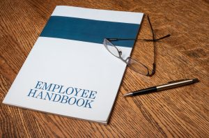 Employee handbook manual on a desktop with glasses and a mechanical pencil